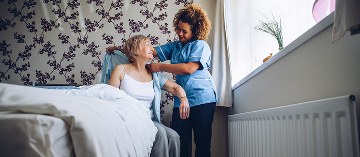 Home care worker helps senior woman get changed after waking up in the morning.