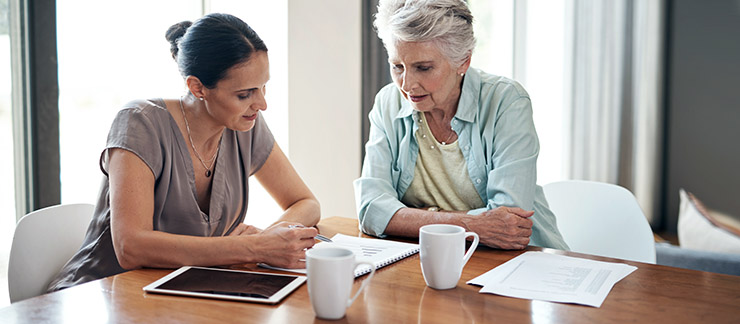 Senior woman sitting at table with daughter to organize medical files to be used in case of an emergency.