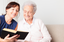 visiting angel reading to woman